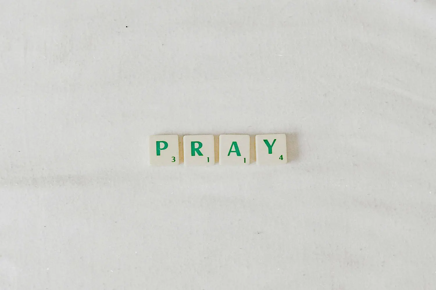 Green Scrabble pieces that spell "PRAY"