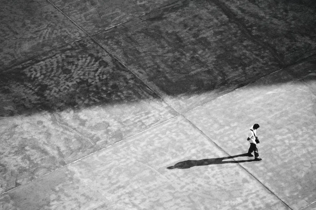 A man walking alone, casting a long shadow