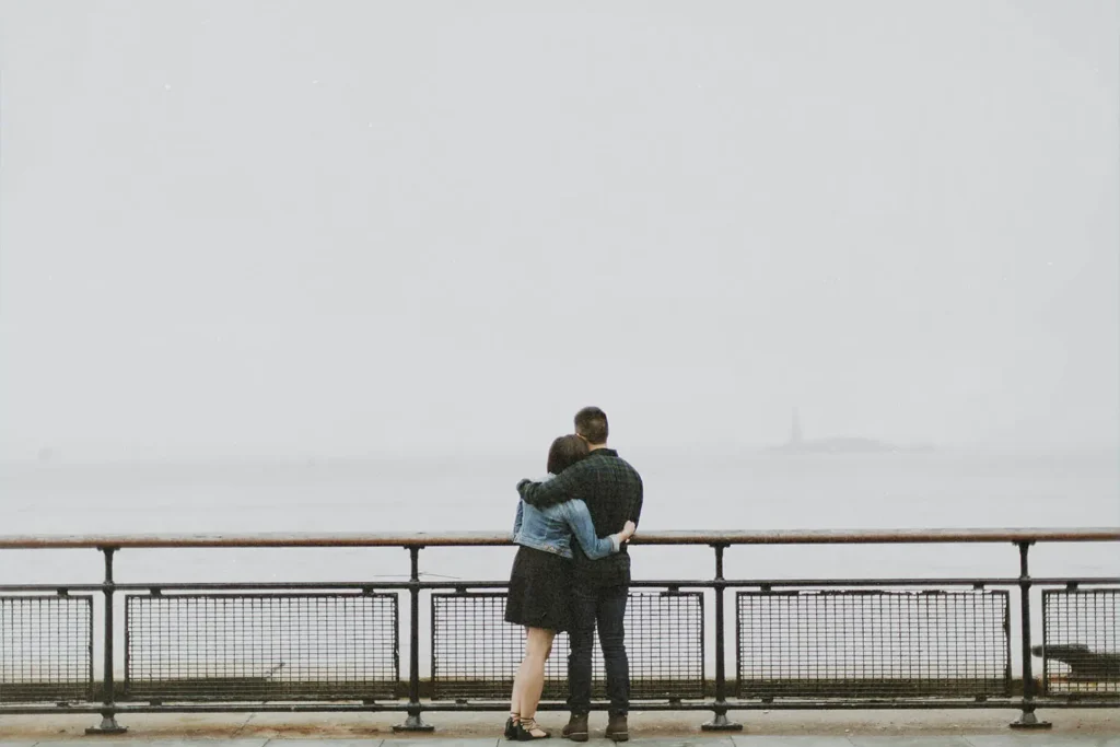 Couple standing at railing hugging each other