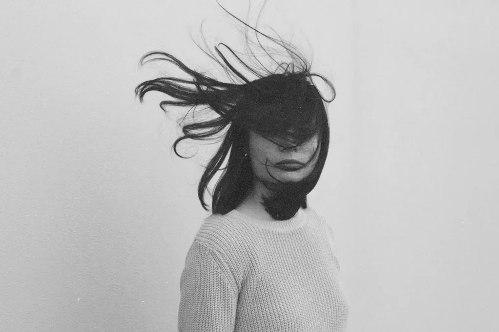 Person facing forward with their hair blowing in their face