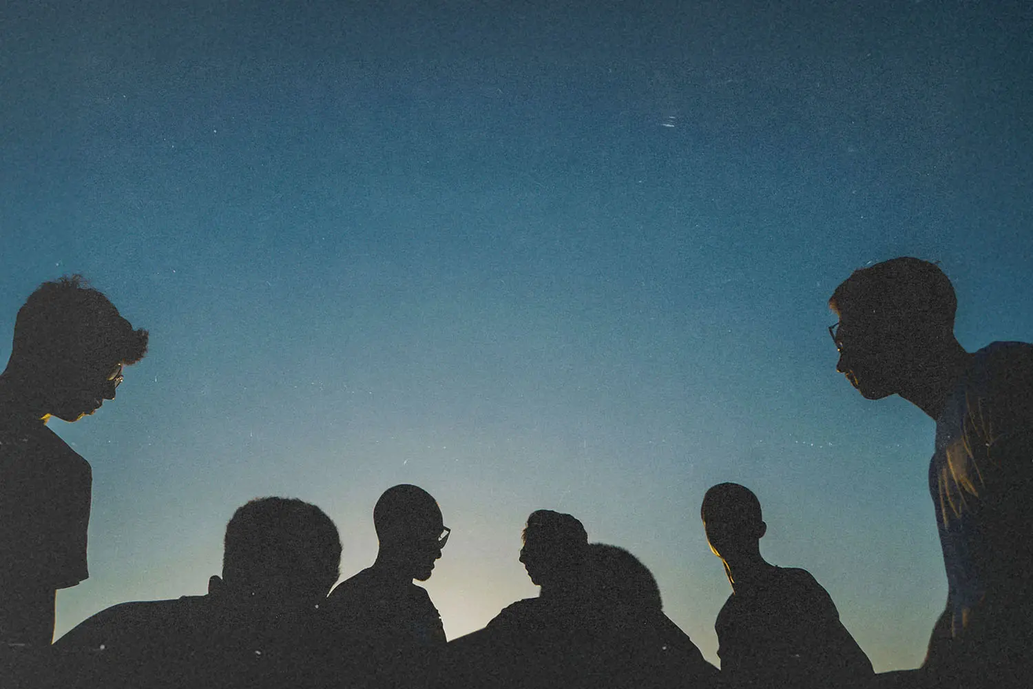 silhouette of people standing in front of a sunset