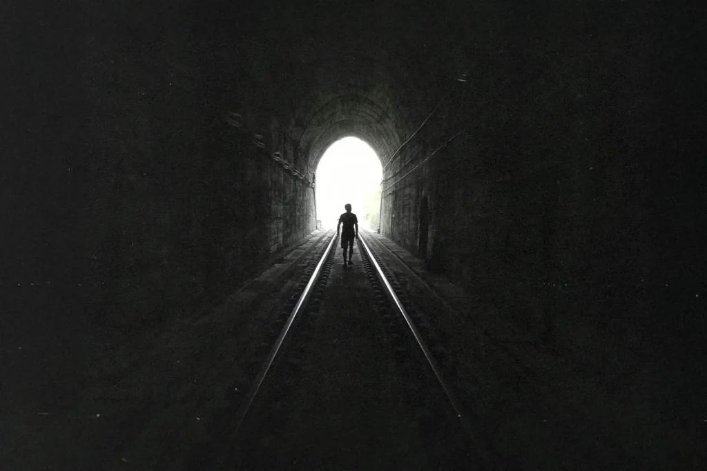 How-to-Go-From-Hope-To-Harvest-KCM - KCM Blog Man walking on train tracks in a tunnel towards light