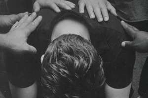 Laying hands in prayer on a man crouched over