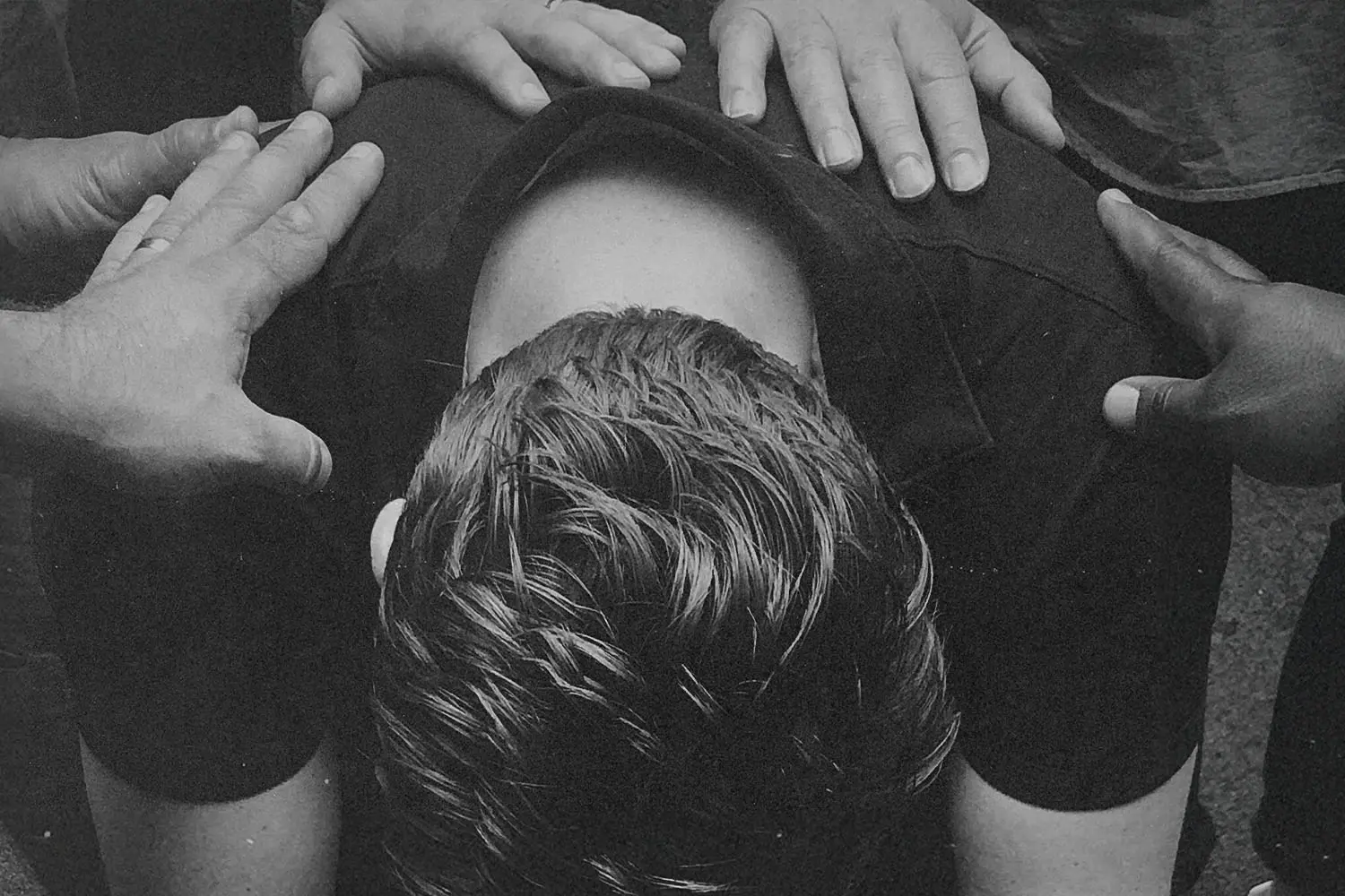 Laying hands in prayer on a man crouched over