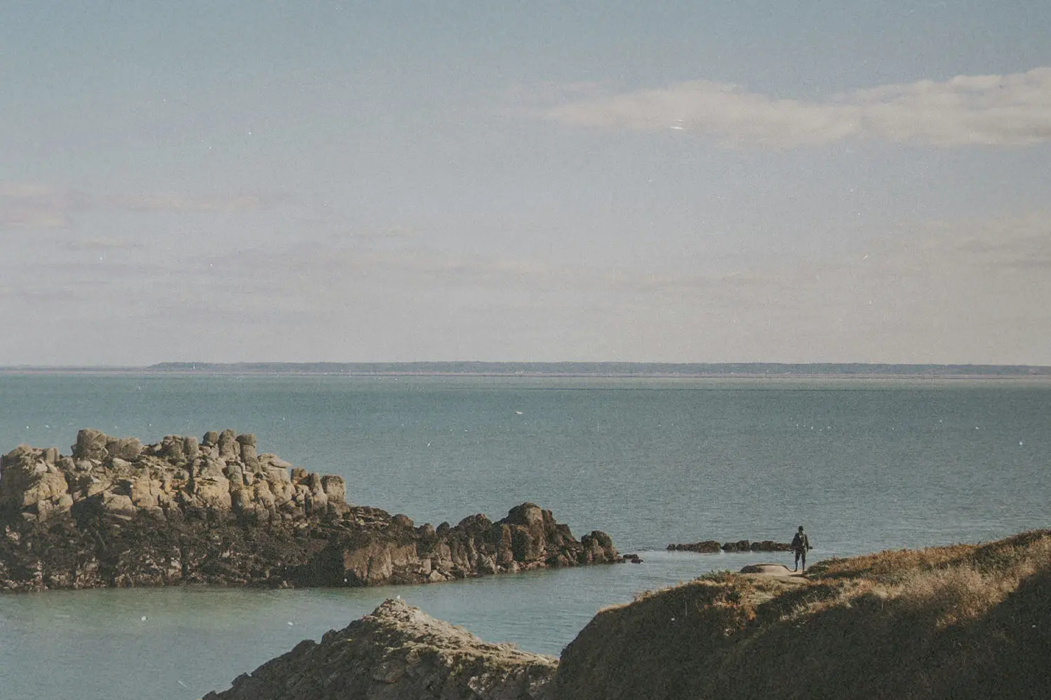 boulders coming up from a calm ocean