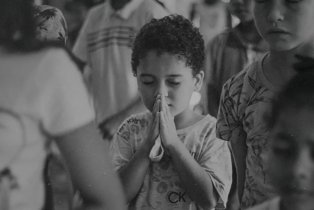 Little boy with eyes shut tightly and folded hands in prayer