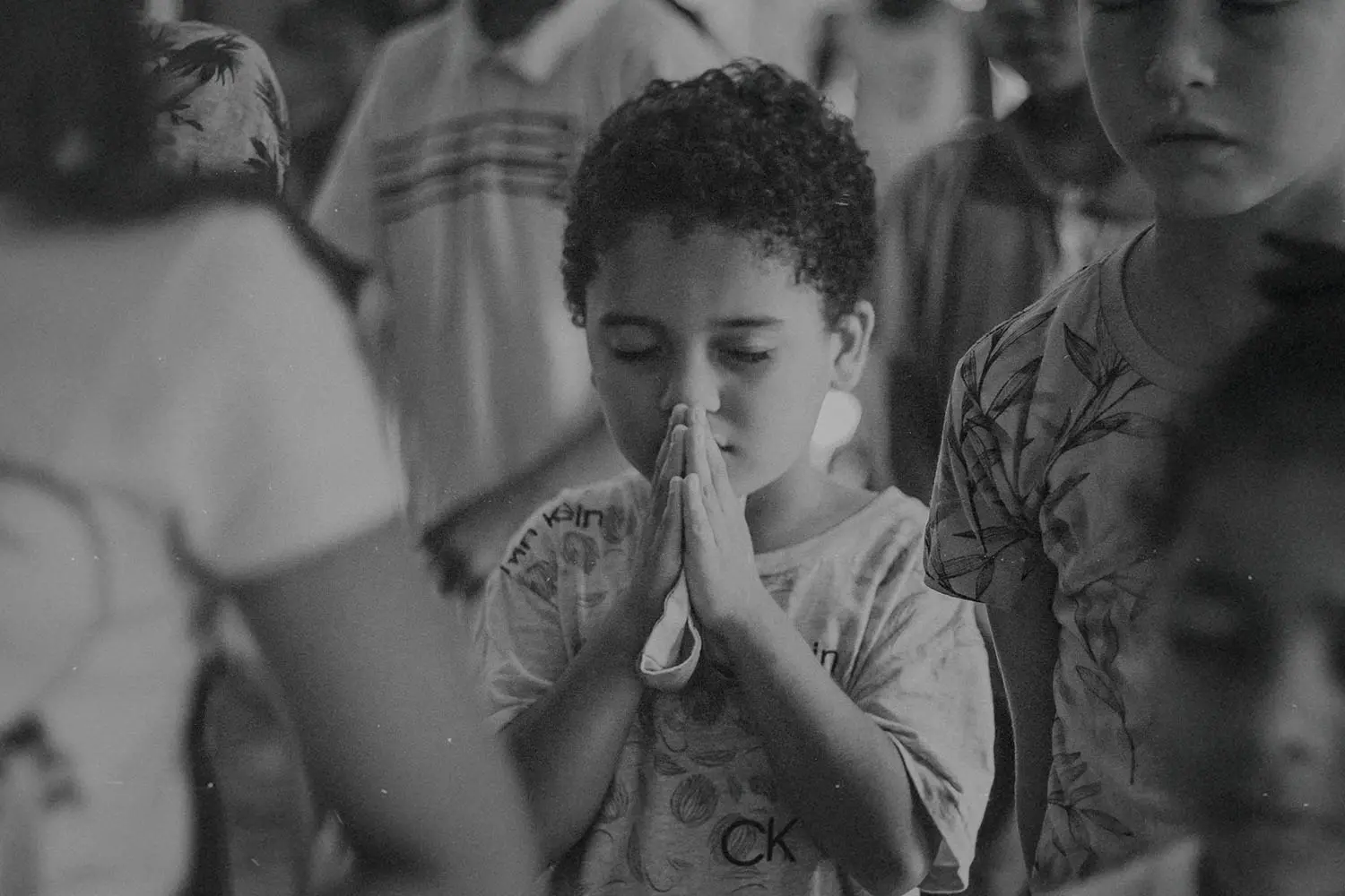 Little boy with eyes shut tightly and folded hands in prayer