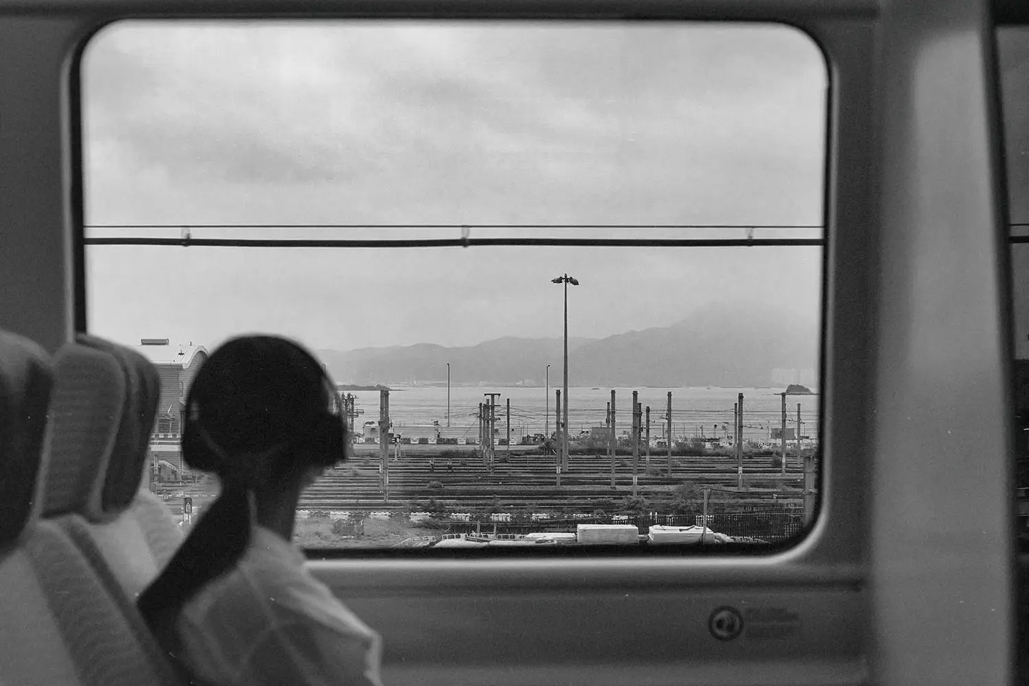 Girl with headphones on looking out a train window towards the city
