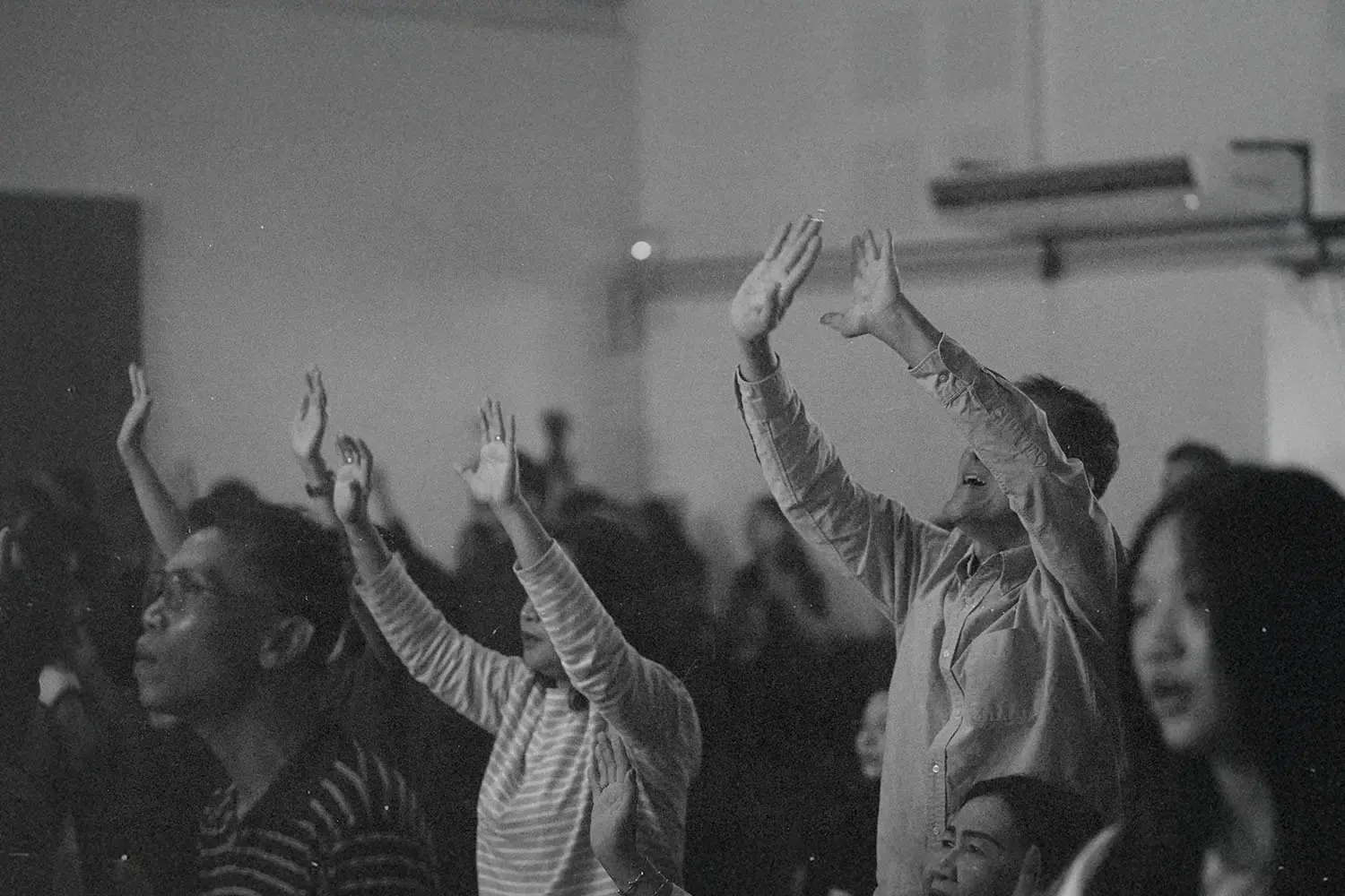 Crowd of people lifting hands and heads in worship