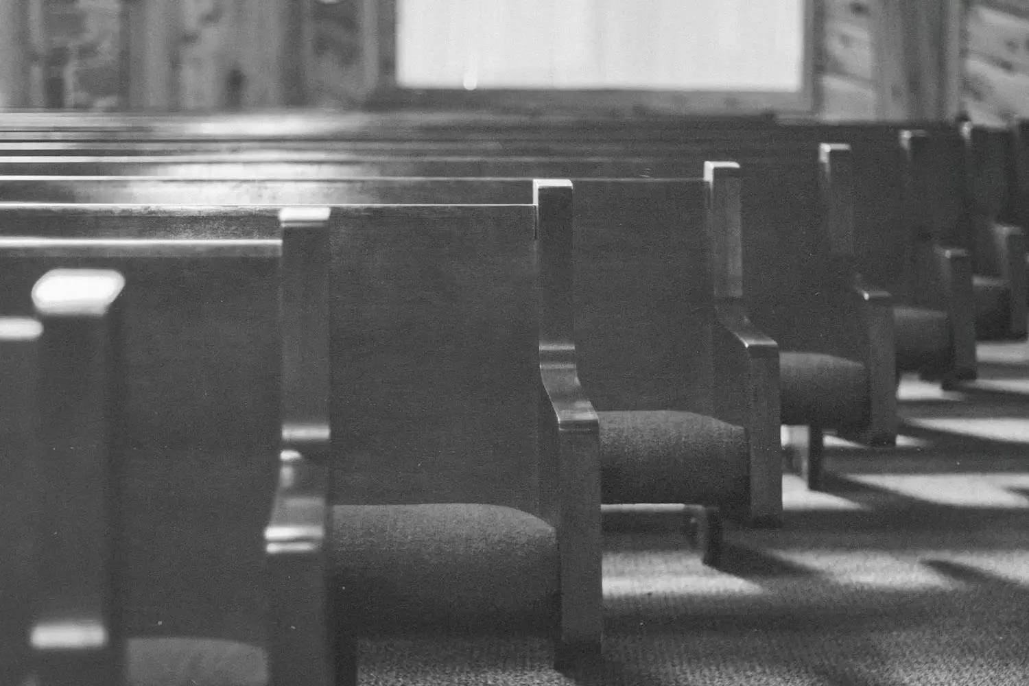 black and white photo of empty church pews