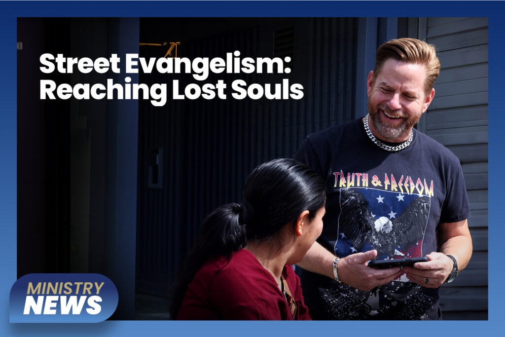 A young man smiling, wearing a “Truth and Freedom” eagle T-shirt, is chatting with a young woman outside on a sunny day.