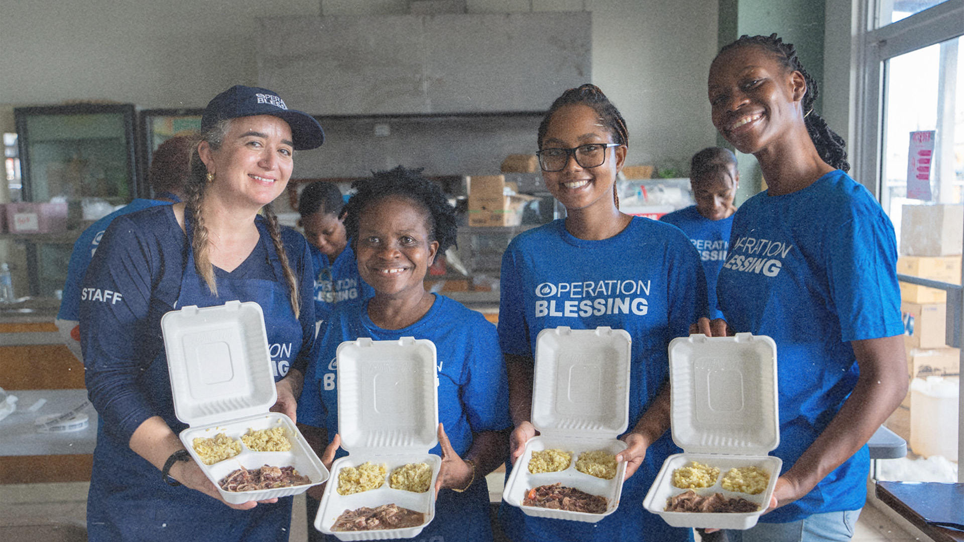 Operation Blessing team holding meal boxes with rice and meat, supporting local communities with food assistance.