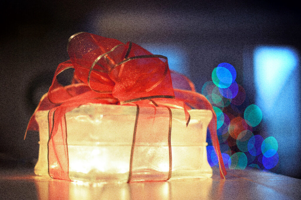 Glowing gift box wrapped with a red ribbon, symbolizing light, hope, and the message that Jesus transforms lives.