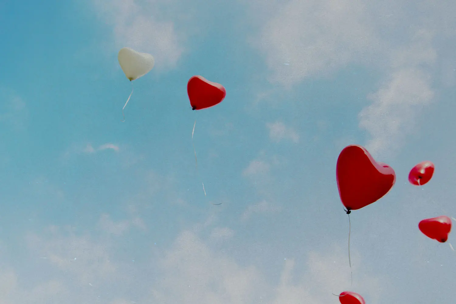 Red heart balloons flying through the sky