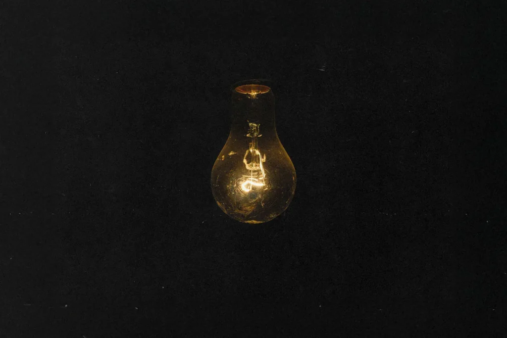 Dark background with a dimly lit light bulb hanging