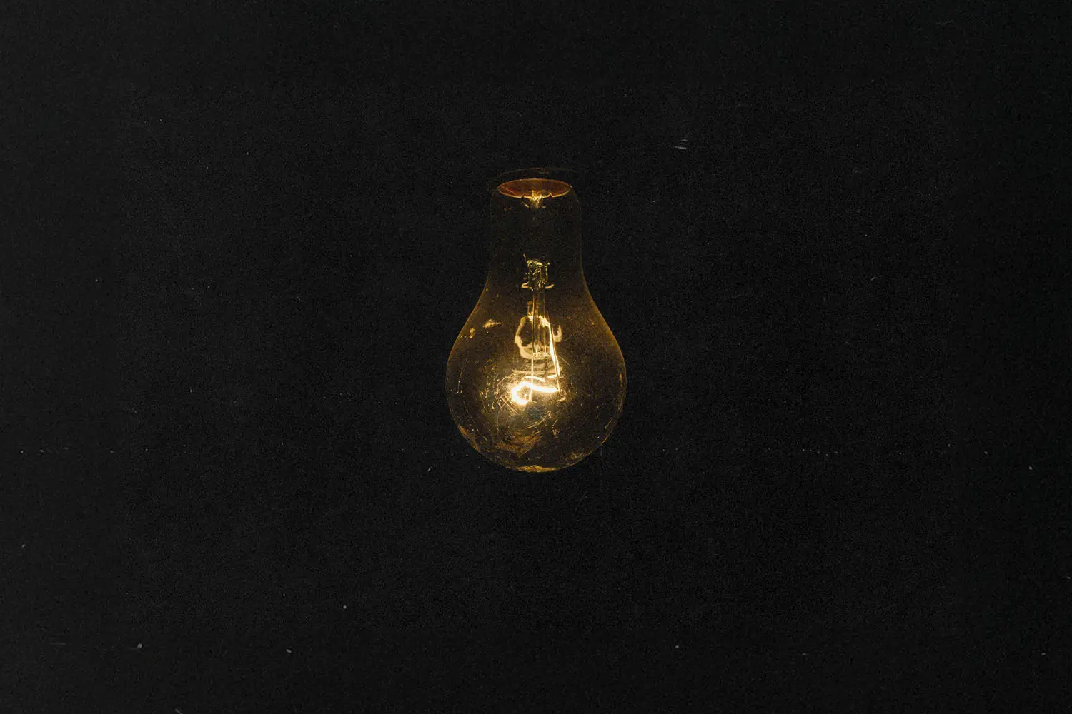 Dark background with a dimly lit light bulb hanging