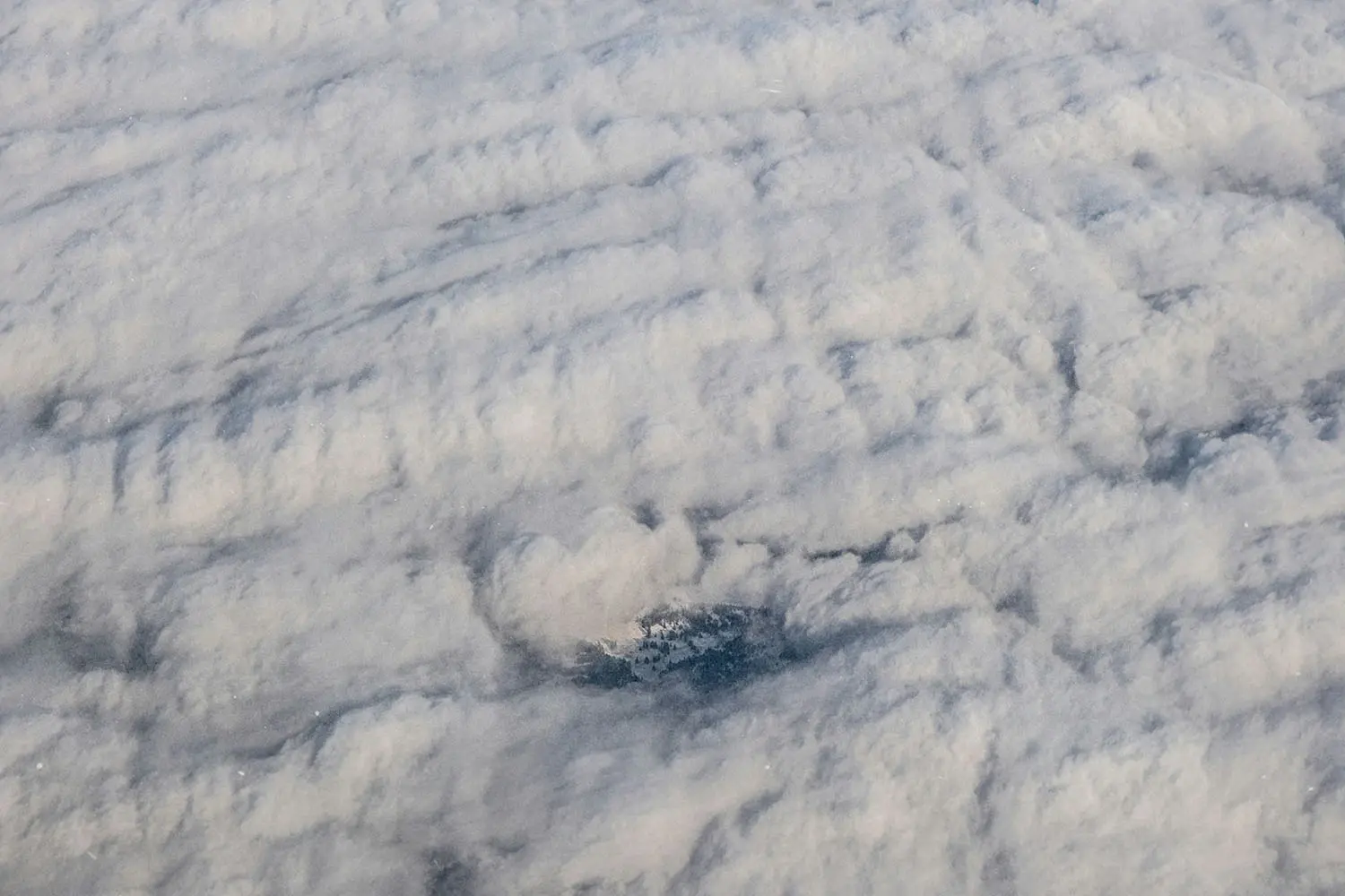Shot of clouds from above with small town peeking through
