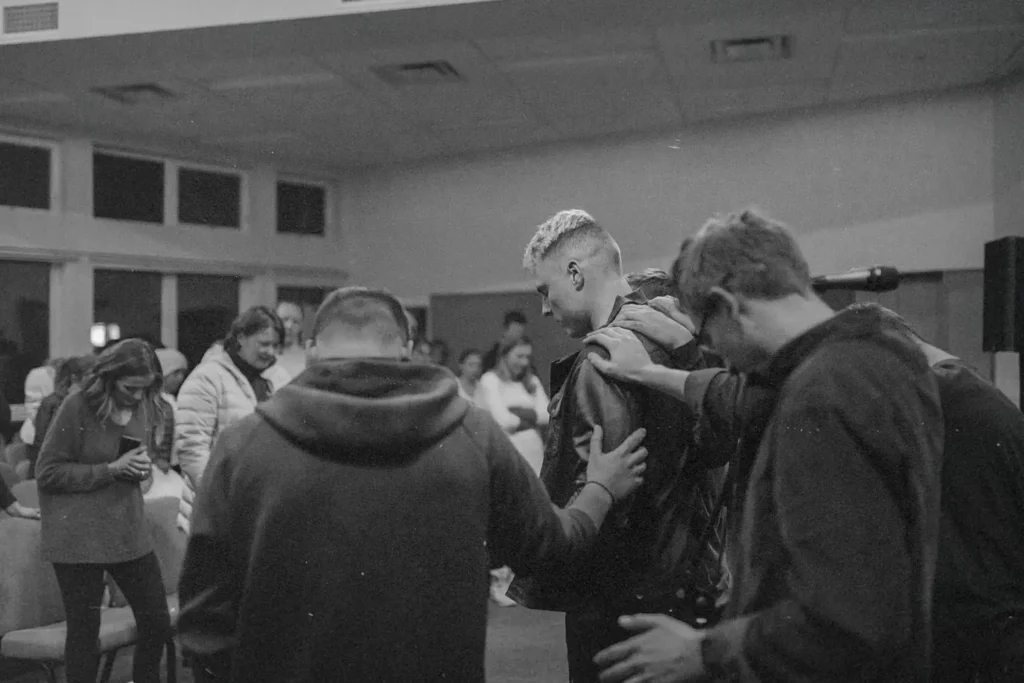 Group of people huddled , laying hands on each other, and praying