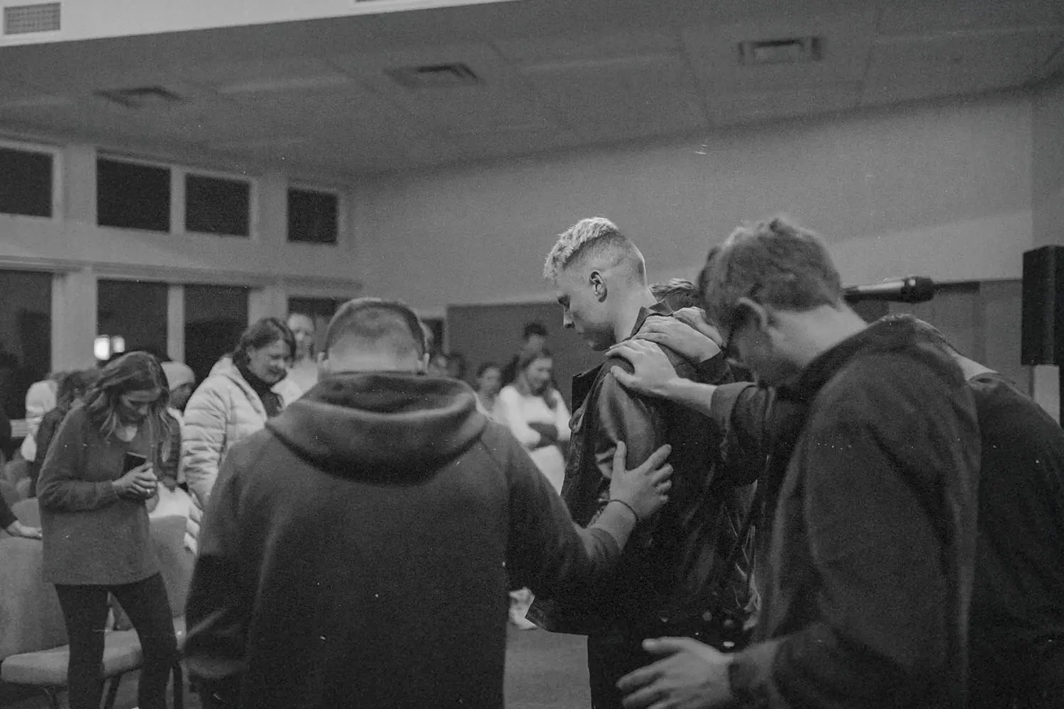 Group of people huddled , laying hands on each other, and praying