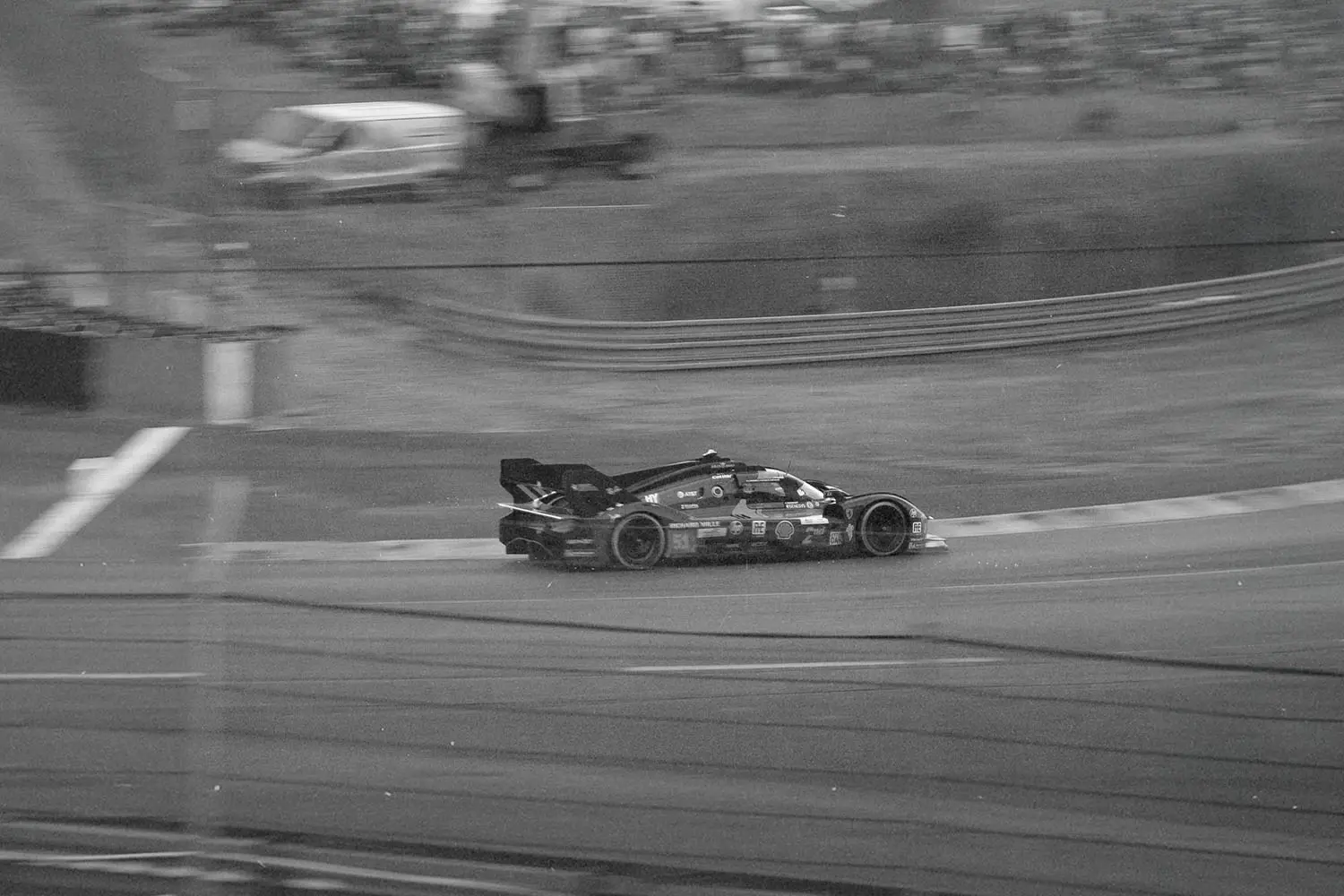 black and white photo of race car driving on track