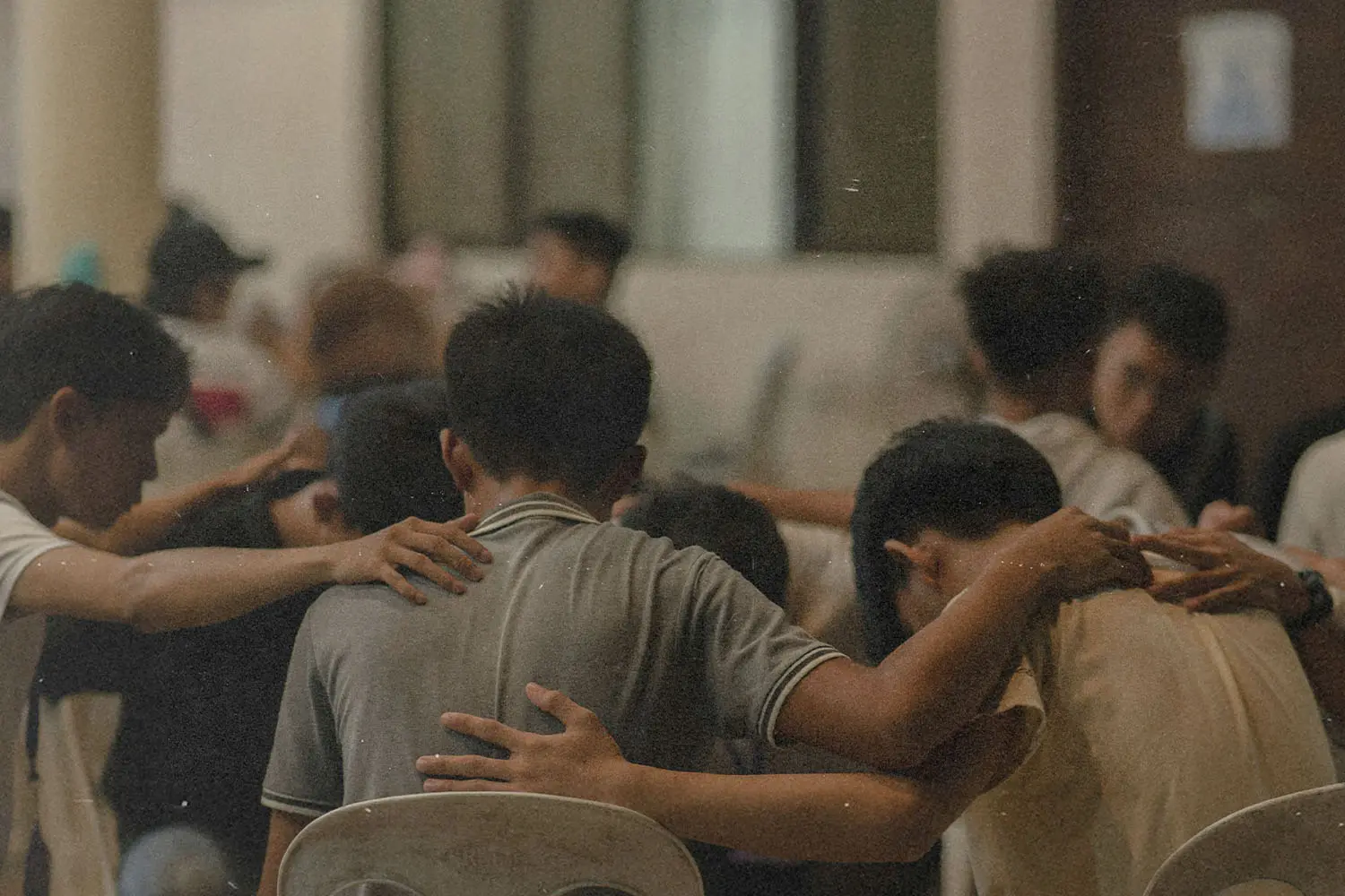 group of people with hands on each others shoulder with heads down