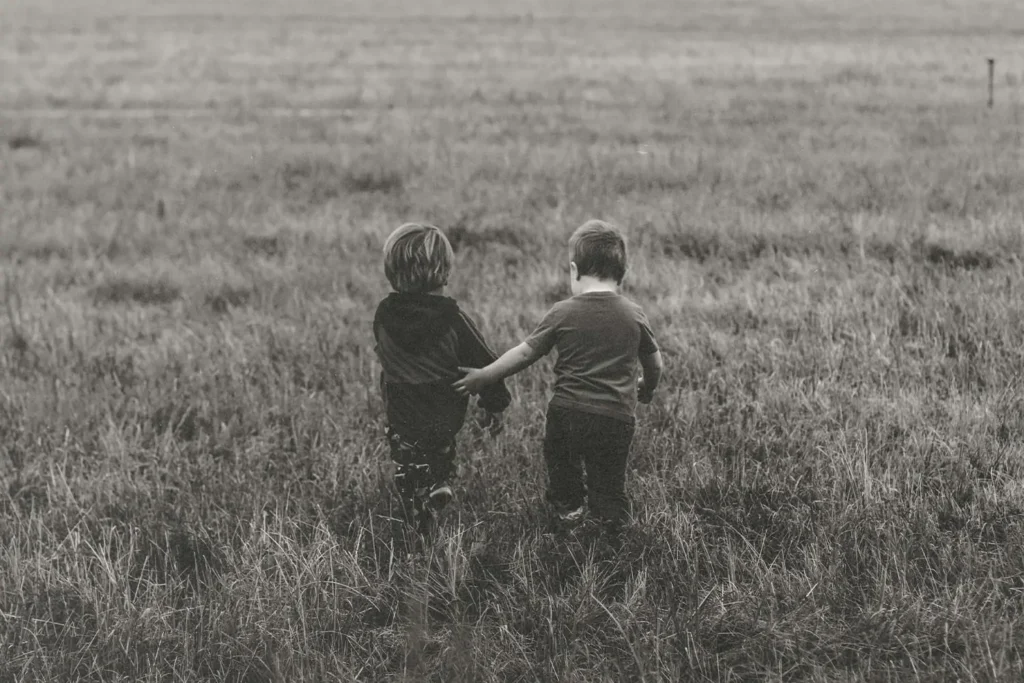 Two kids walking through a field