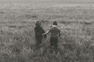 Two kids walking through a field