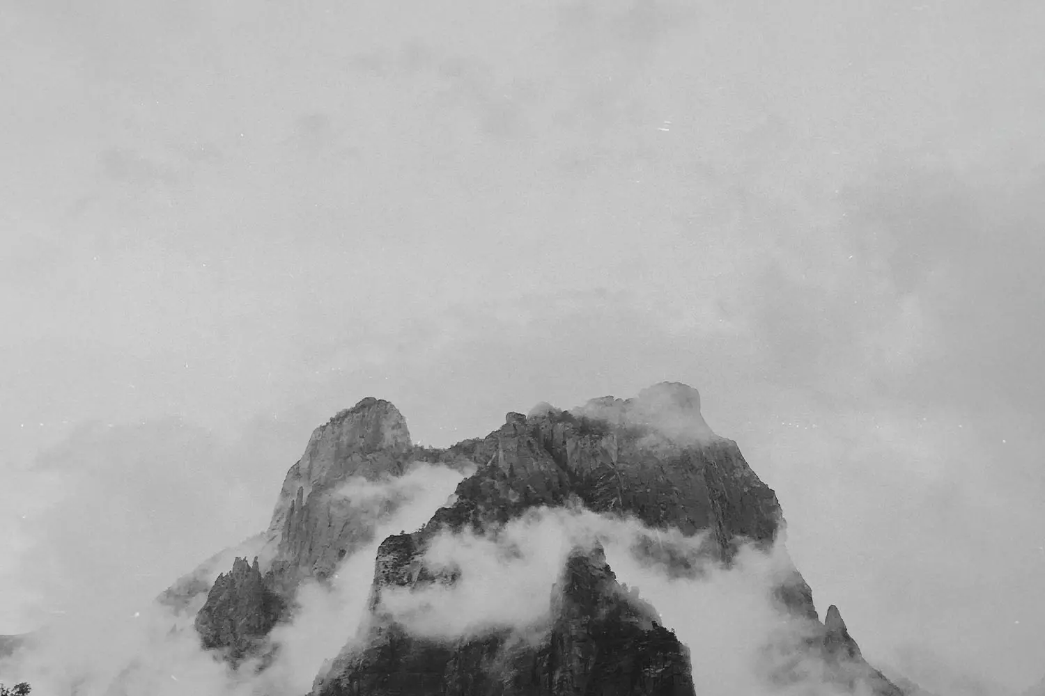 Black and white image of fog resting on mountain peak