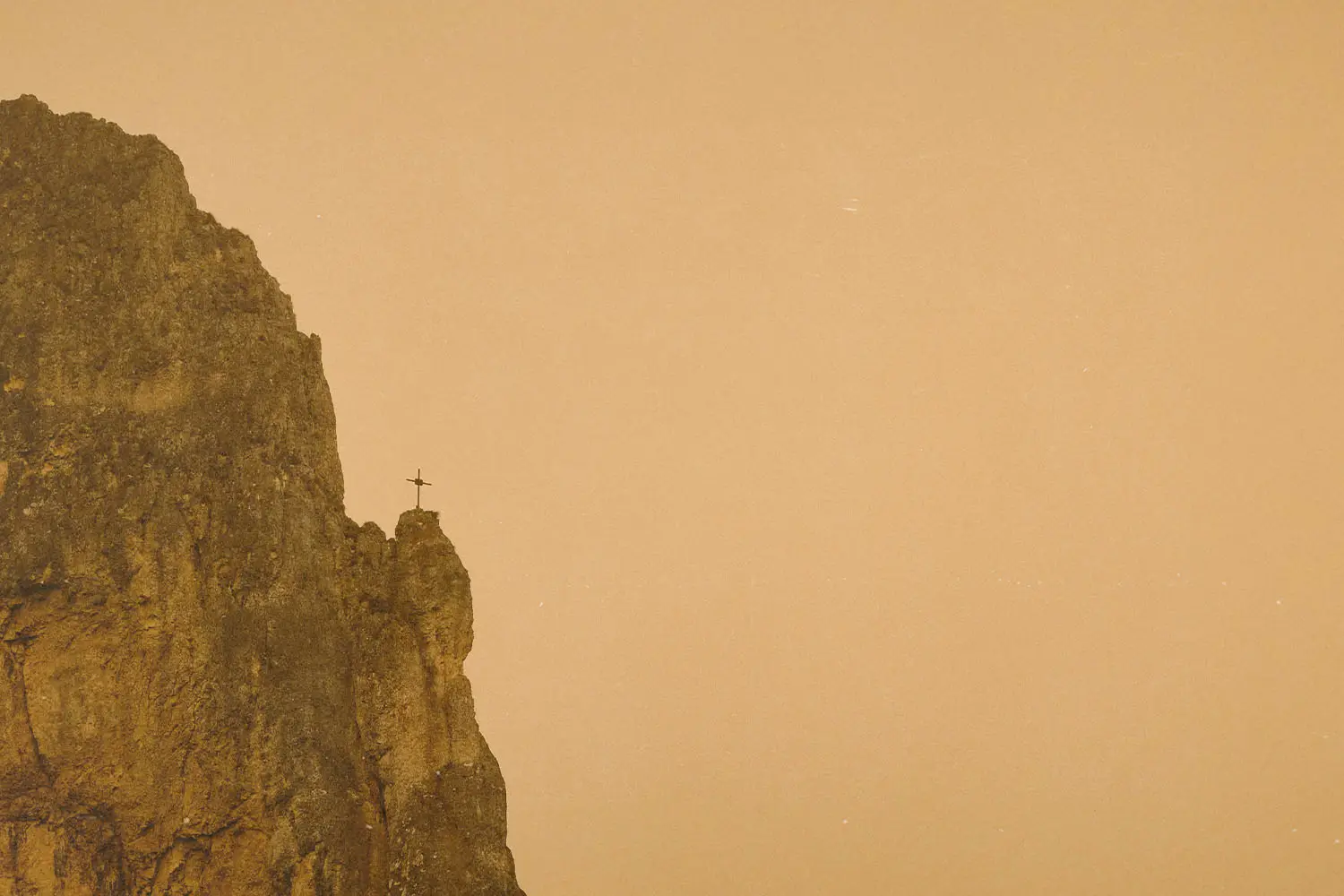 Cross on the edge of a cliff in the distance