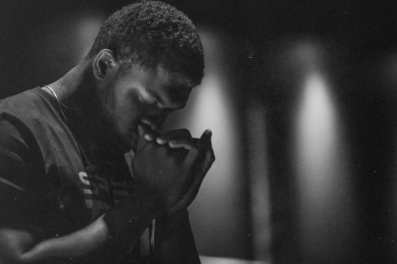 Man with head bowed and hands clasped to pray
