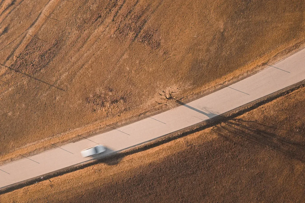 Blurred car driving on a open road with dry farm lands on both sides