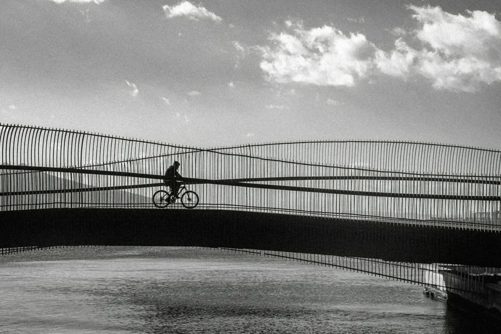 person on a bike riding over a bridge with water underneath