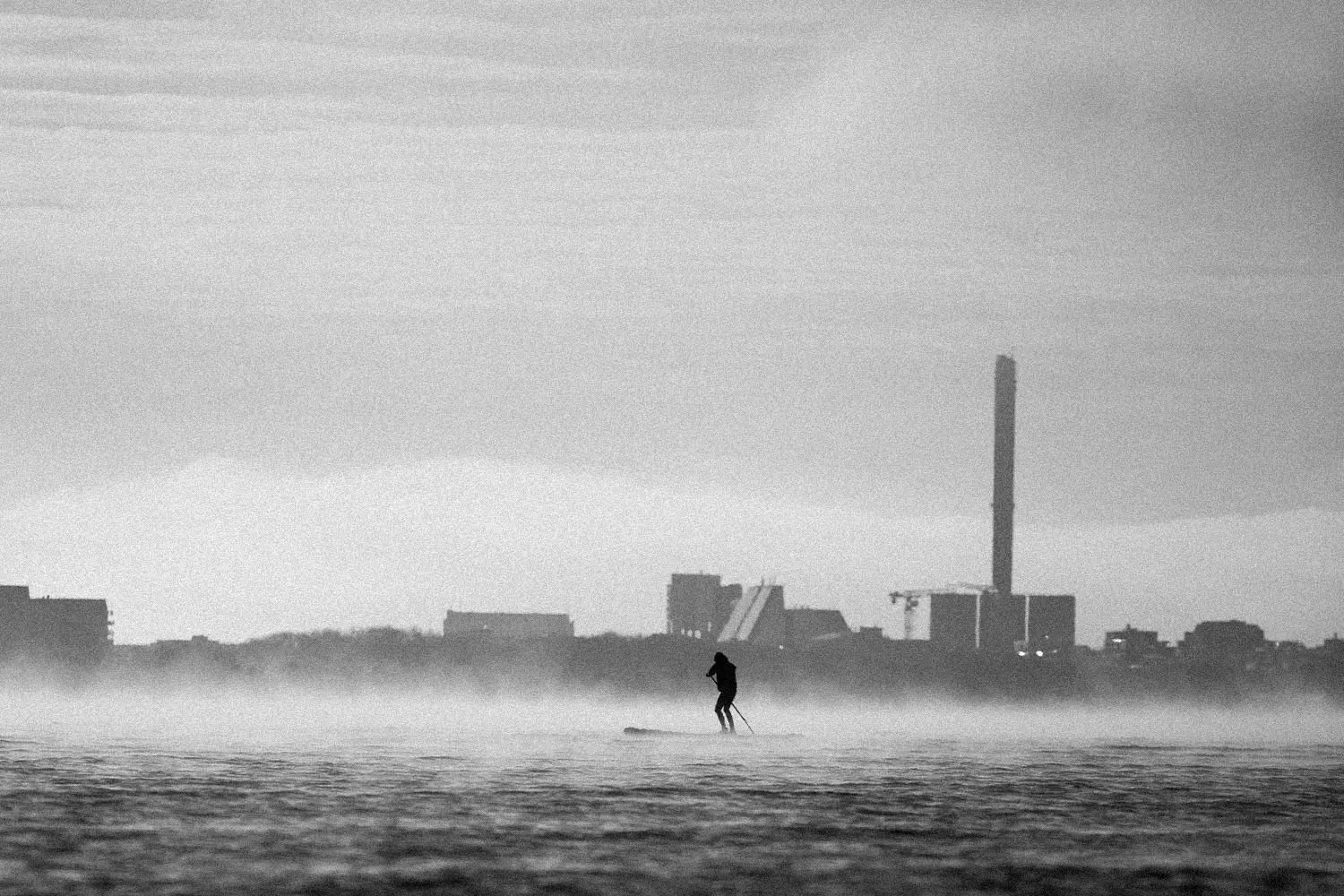 Person standup paddle boarding in the middle of rushing waters