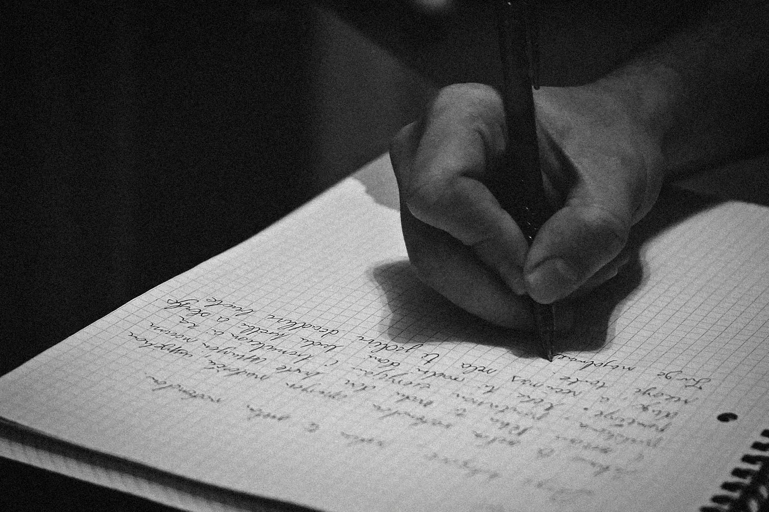 Hand holding a pen writing cursive in a notebook