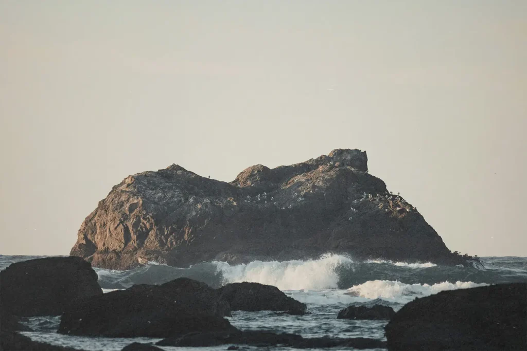 big rock sticking out of rough ocean