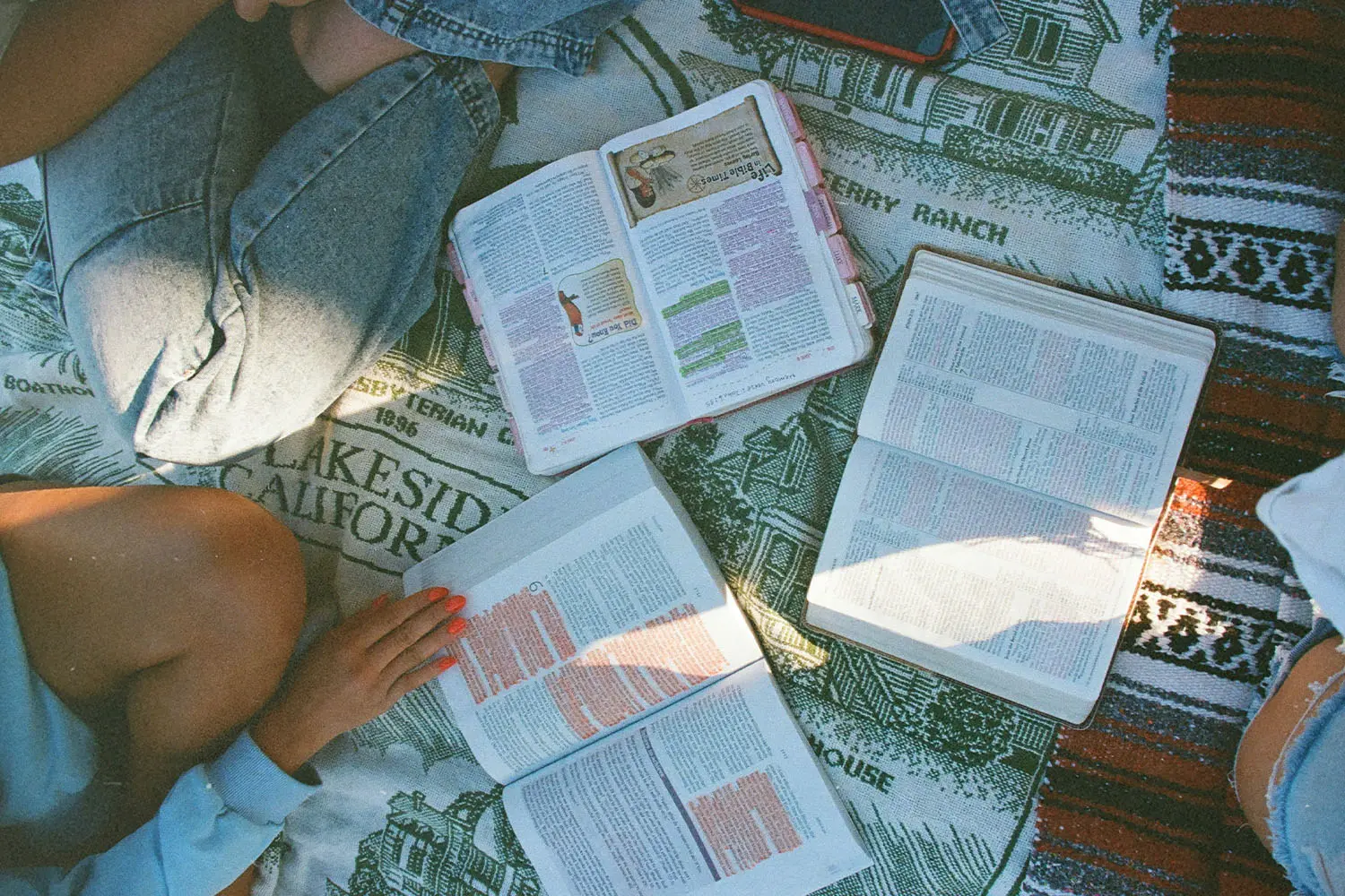 Group of 3 people sitting crisscross with Bibles open on the floor