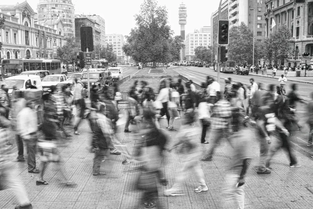 lots of people walking across a crosswalk with a blur for the look of speed