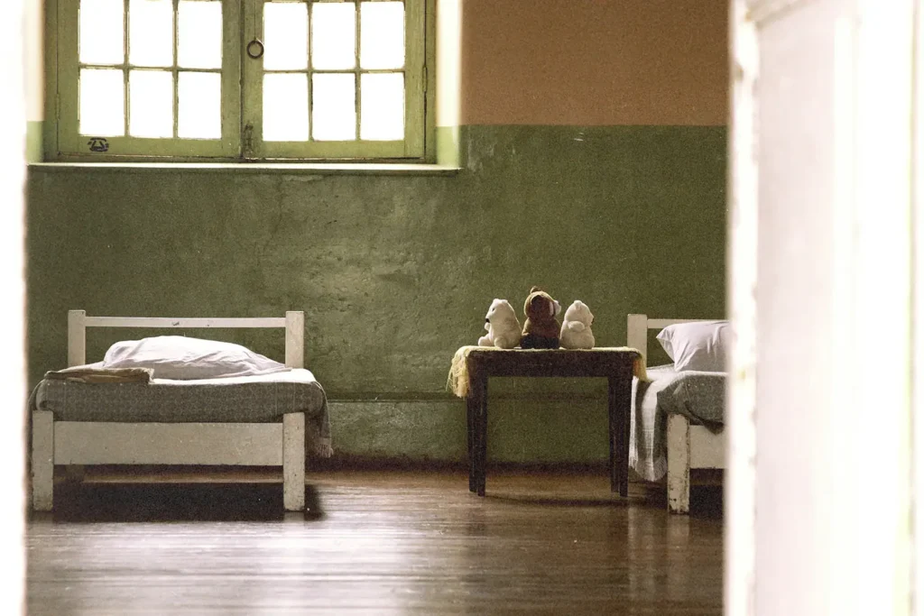 Bedroom with two twin beds and single side table with stuffed animals on top