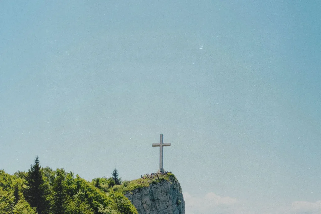Stone cross on the edge of a rock cliff with clear skies in the background