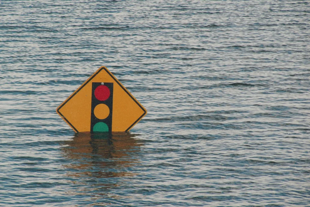 Flood waters that almost cover a traffic light sign
