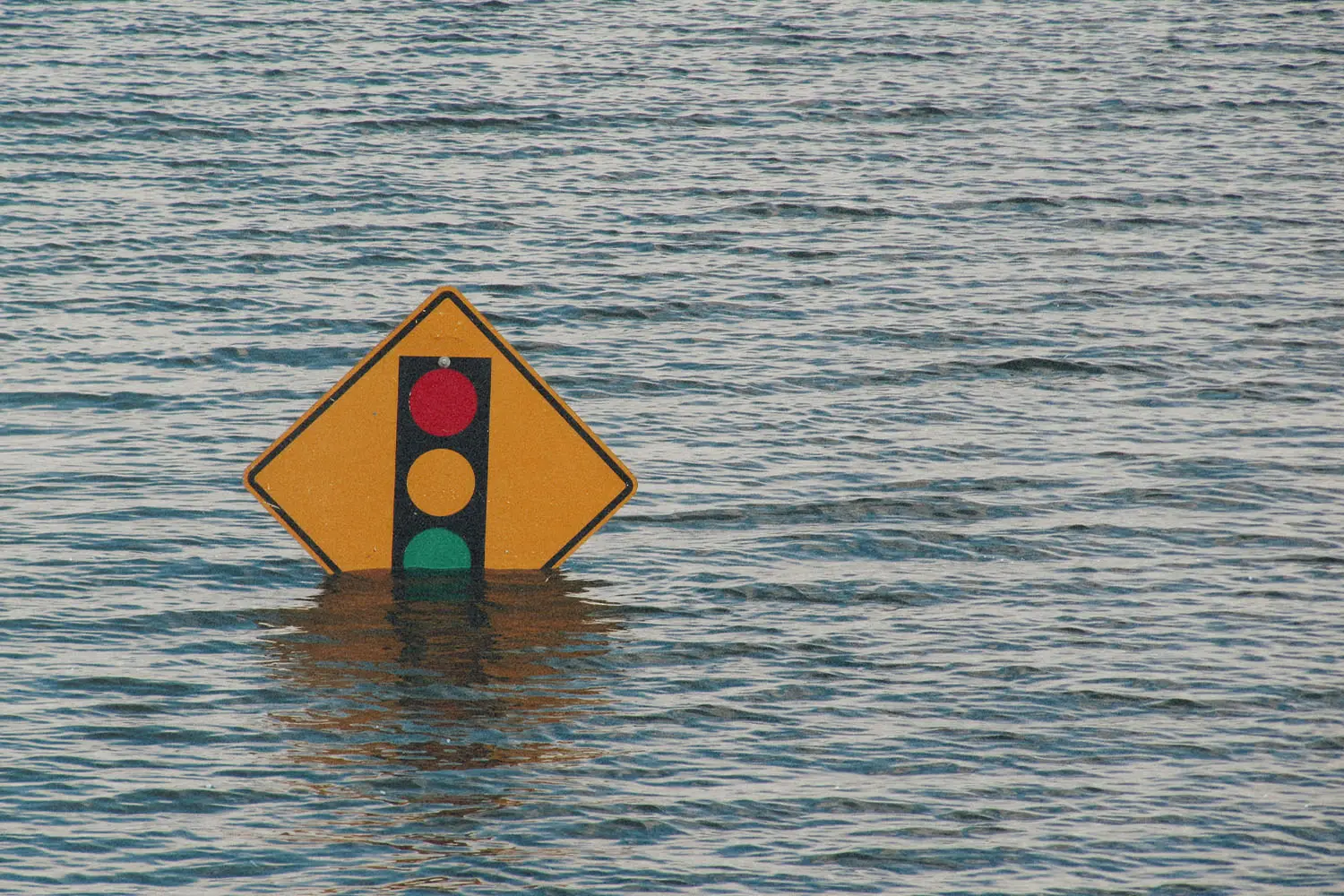 Flood waters that almost cover a traffic light sign