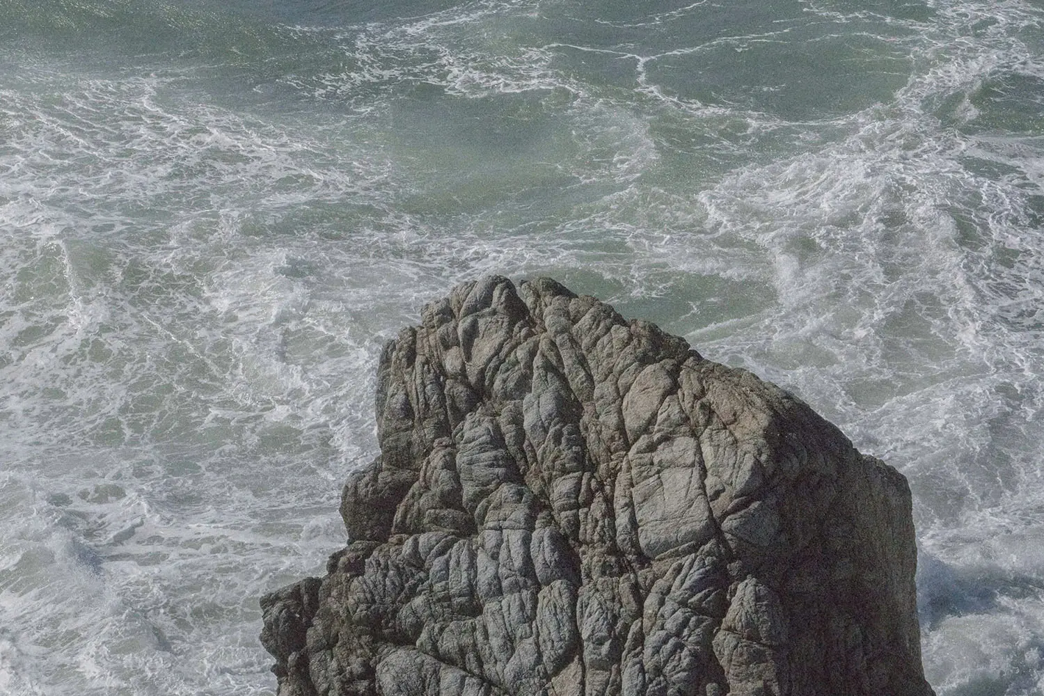 Large rock in the middle of crashing ocean waves