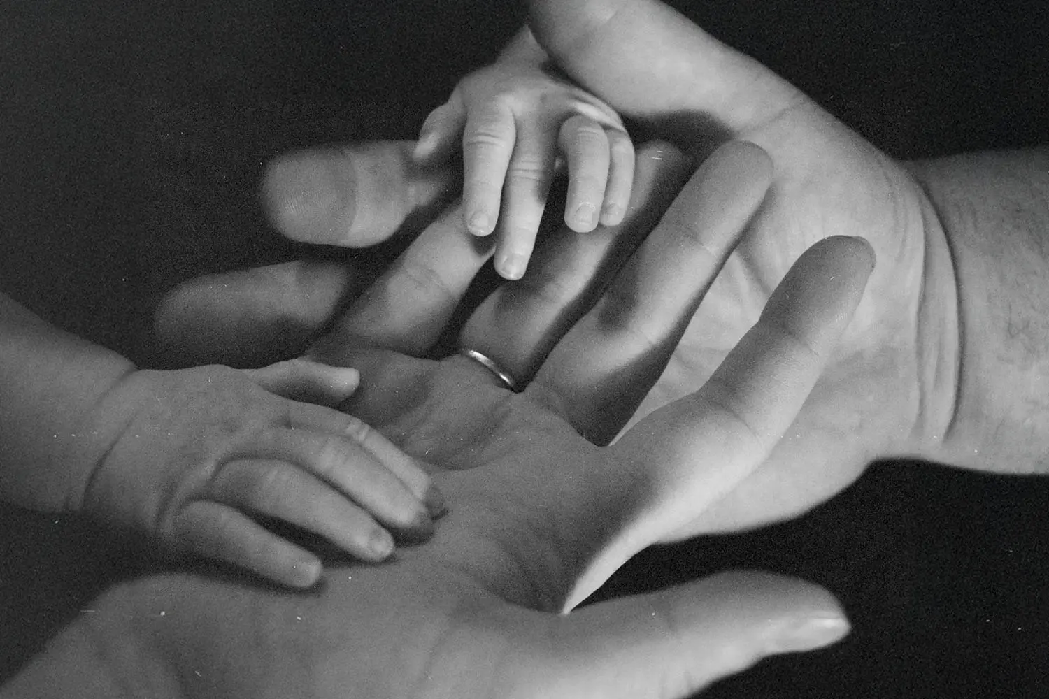 Two baby hands on top of two adult hands