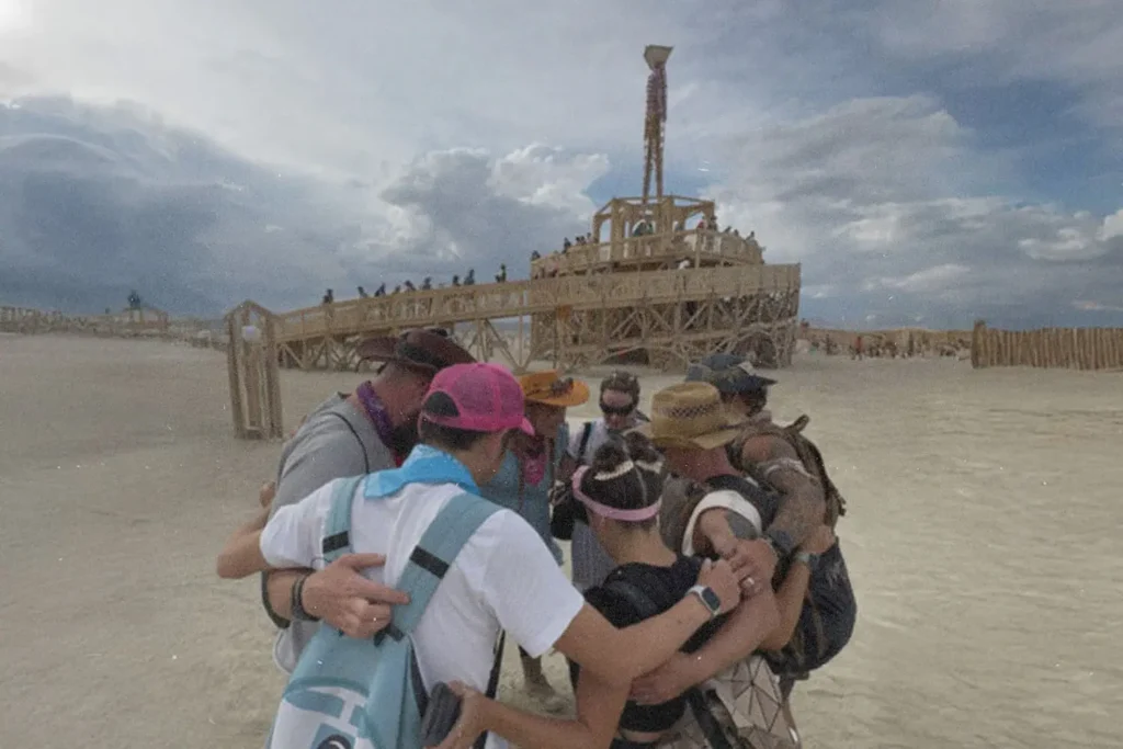 Group of people huddled in prayer at Burning Man Festival