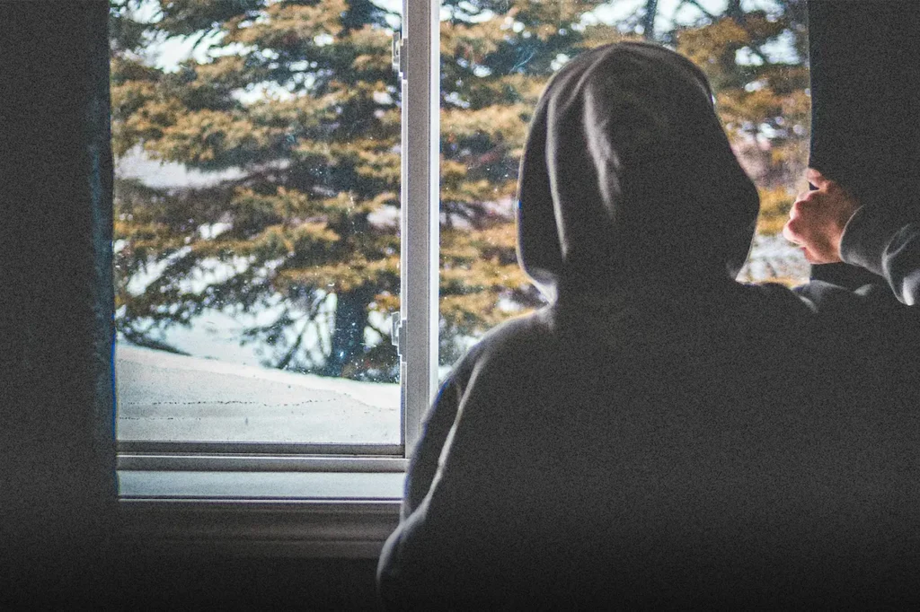 A person in a hoodie looks out a window on a cold day, reflecting on doubt and hope, symbolizing someone you love who may be questioning God in a hard season.