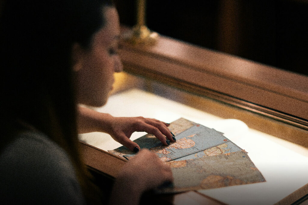 Hands sorting vintage maps on a softly lit table, symbolizing God’s plan and Your life unfolding through guidance, direction, and purposeful steps.