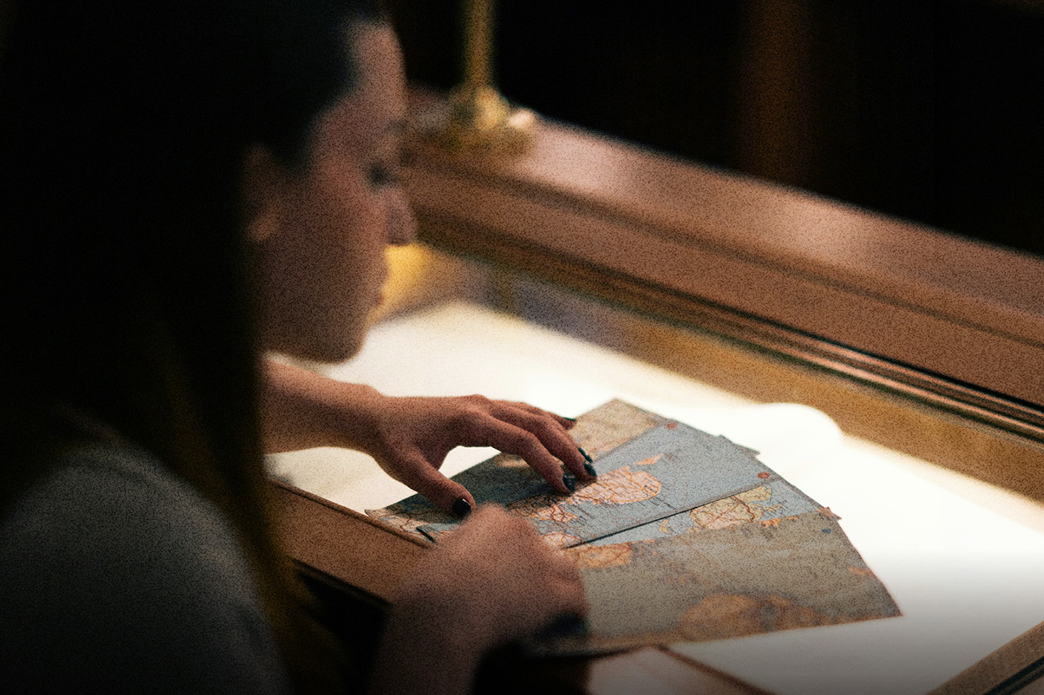 Hands sorting vintage maps on a softly lit table, symbolizing God’s plan and Your life unfolding through guidance, direction, and purposeful steps.