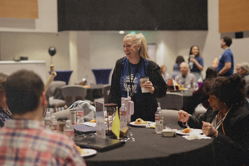 People gathered at round tables in a church setting, discussing faith while holding coffee, reflecting how God’s Word supports personal wellness.